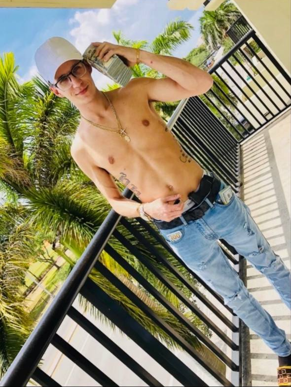 Ray Trapani on a palm-lined balcony holding stacks of cash